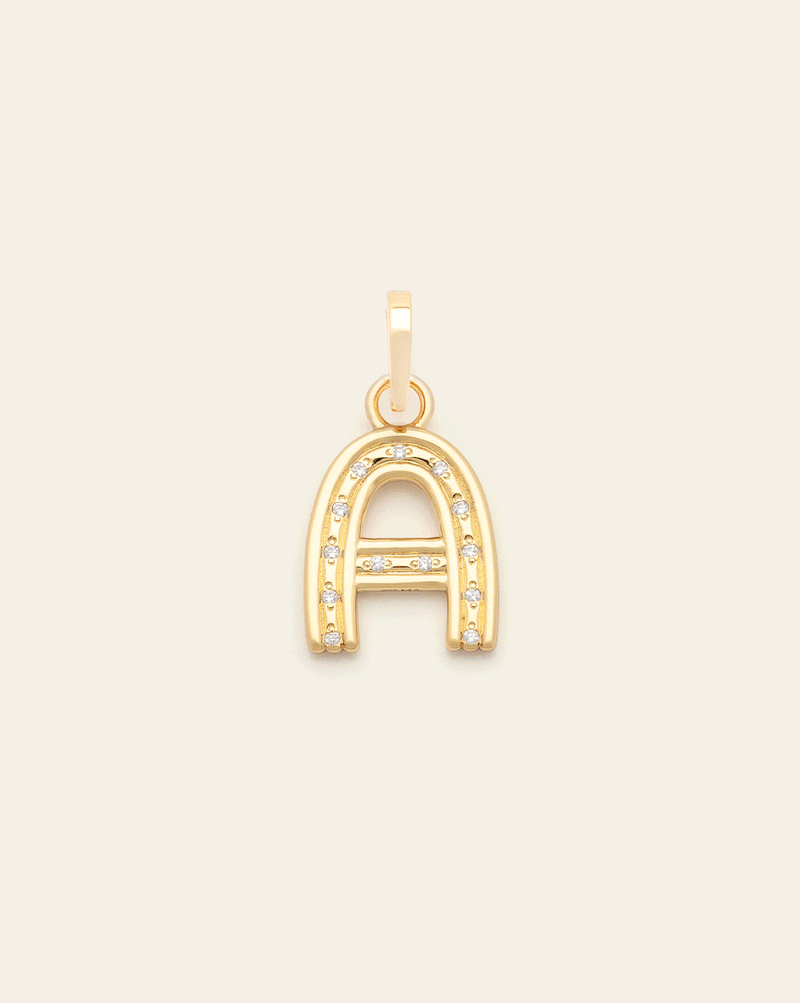 Animated image of a gold vermeil letter charms flashing through alphabet charms embellished with small sparkling stones along the front, displayed against a light beige background.