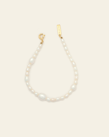 Product image of freshwater pearl bracelet with gold vermeil clasp and MAJ logo tag on cream background.