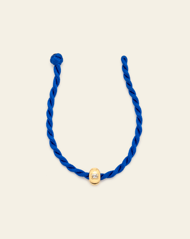 Cobalt blue twisted cord bracelet featuring a polished gold vermeil spacer with a single cut cubic zirconia stone, displayed on a neutral background. 