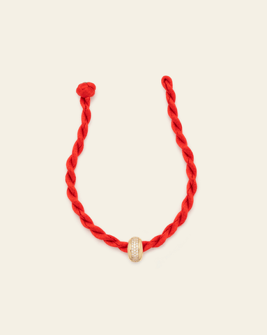 Red twisted cord bracelet with a gold vermeil pavé-set spacer charm, displayed flat on a neutral background.