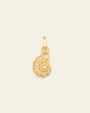 hero image of gold vermeil coquille charm on cream background with cubic zirconia stones.