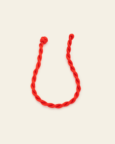 Lobster red twisted cord bracelet styled in a curve, shown on a neutral background with visible knotted ends.