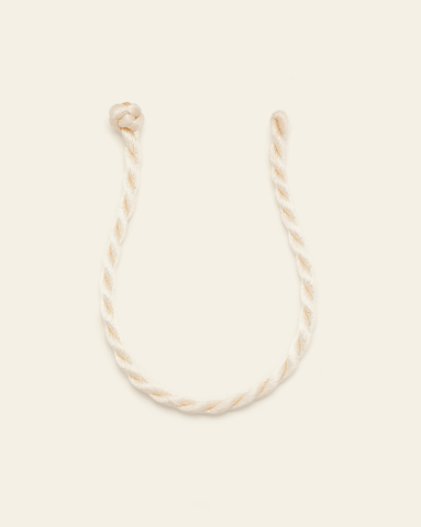 Vanilla-toned twisted cord bracelet with knotted ends on a neutral background.