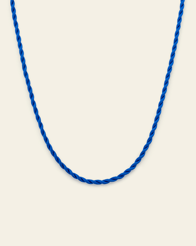 Cobalt blue twisted cord necklace displayed in a curve against a neutral background.