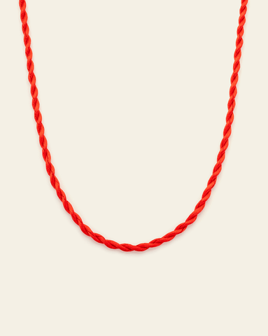 Lobster red twisted cord necklace arranged in a soft curve on a light neutral background.