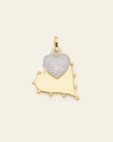 Gold vermeil and silver heart-shaped pendant on a beige background.