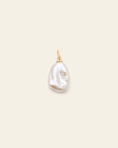 A close up photo of a medium baroque pearl pendant with a Gold Vermeil jump ring on a cream background. 