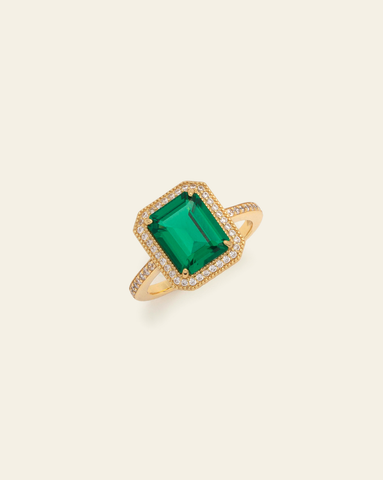 Hero image of gold vermeil emerald ring and cubic zirconia stones on cream background. 