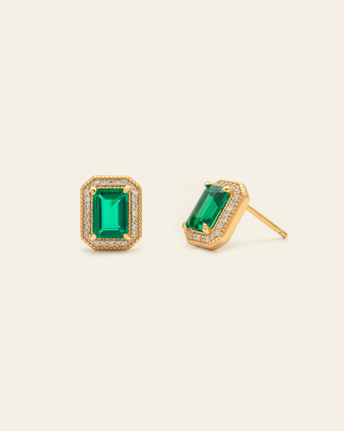 Hero image of Gold vermeil studs featuring a emerald-cut green gemstone surrounded by a halo of clear pavé stones on a cream background.