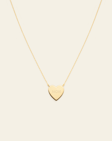 Hero Image of the gold vermeil Heart necklace with the MOM engraving on a cream background.