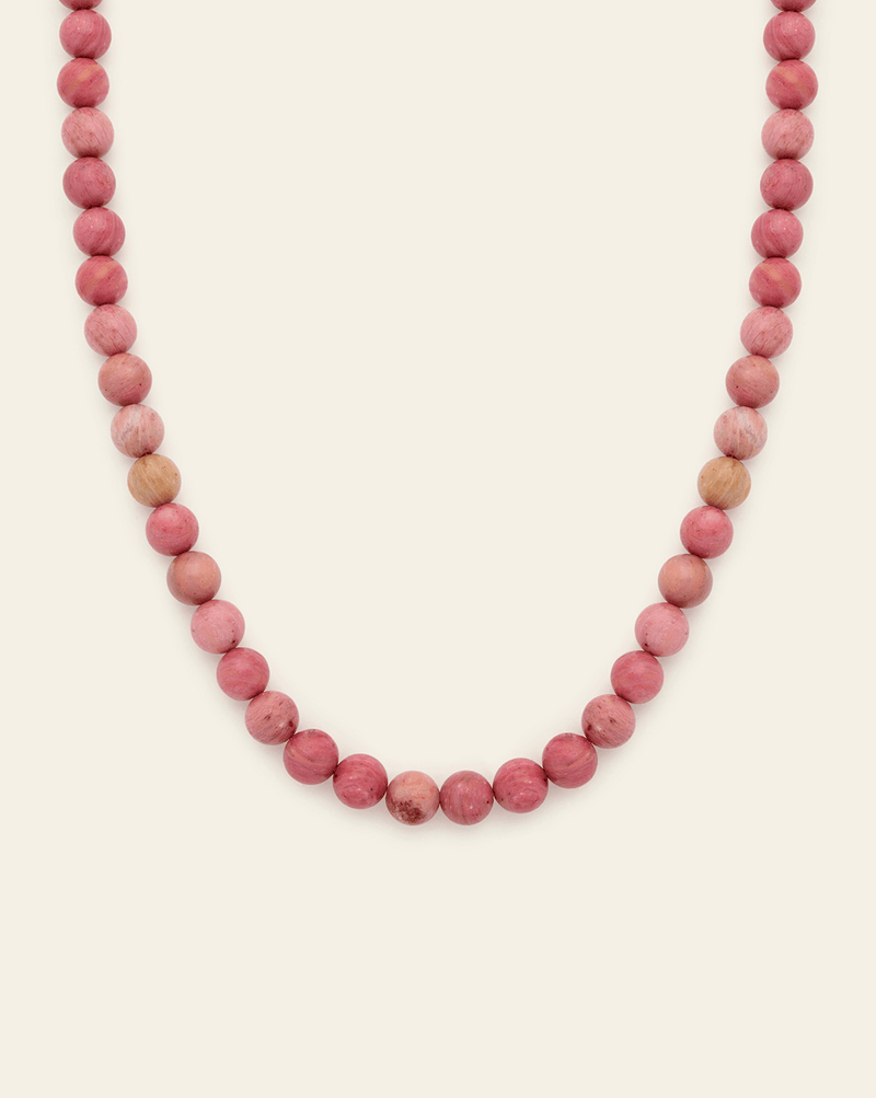 Pink rhodonite bead necklace featuring natural round gemstone beads in soft blush and rose tones on a neutral background.