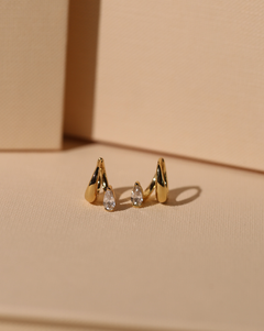 Close up of elegant gold vermeil hoop earring with pear-shaped cubic zirconia stone, styled to look like multiple piercings.