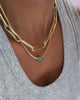 Gold-plated chain necklace with statement link design layered with a petite bezel tennis necklace with an emerald CZ cubic zirconia spacer pendant.